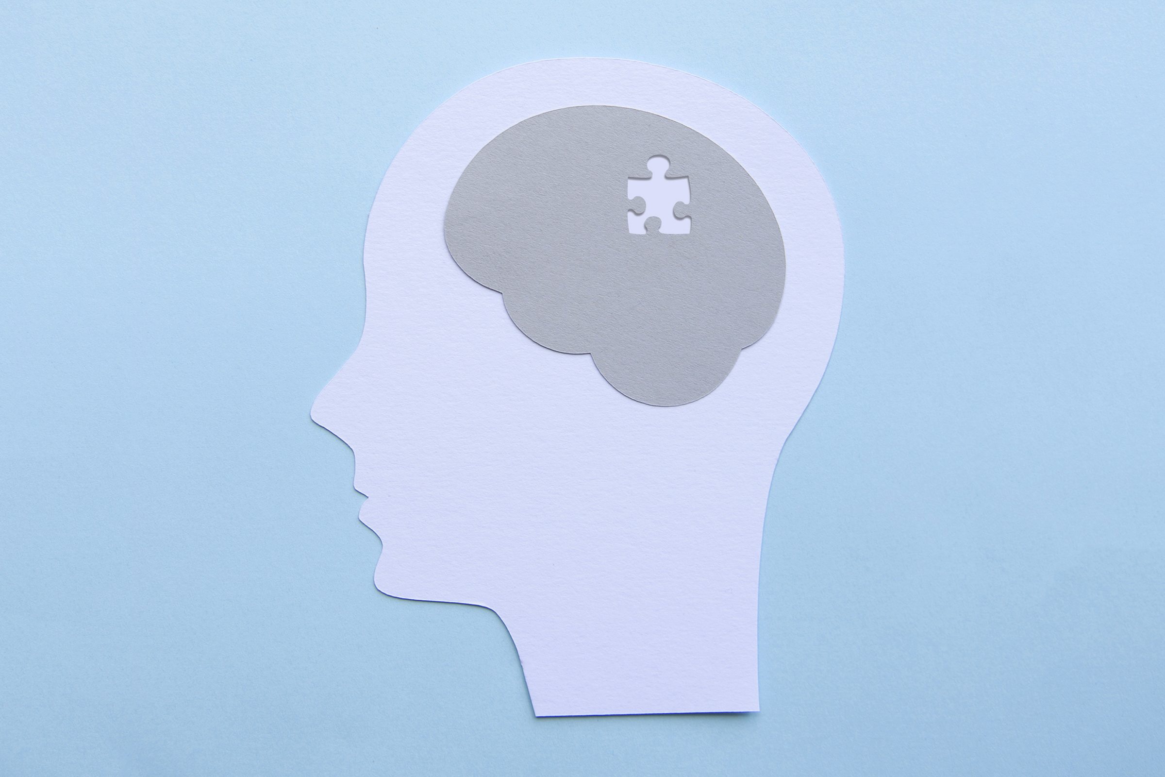 memory concept; paper cutout of human head with puzzle piece missing in the brain