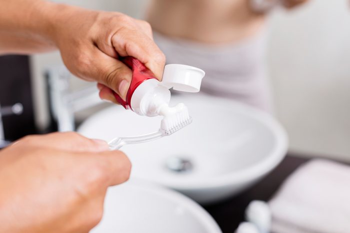 man applying toothpaste onto toothbrush