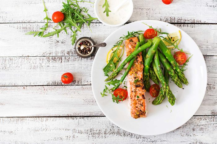 white plate with asparagus, salmon, dill, and lemon slices