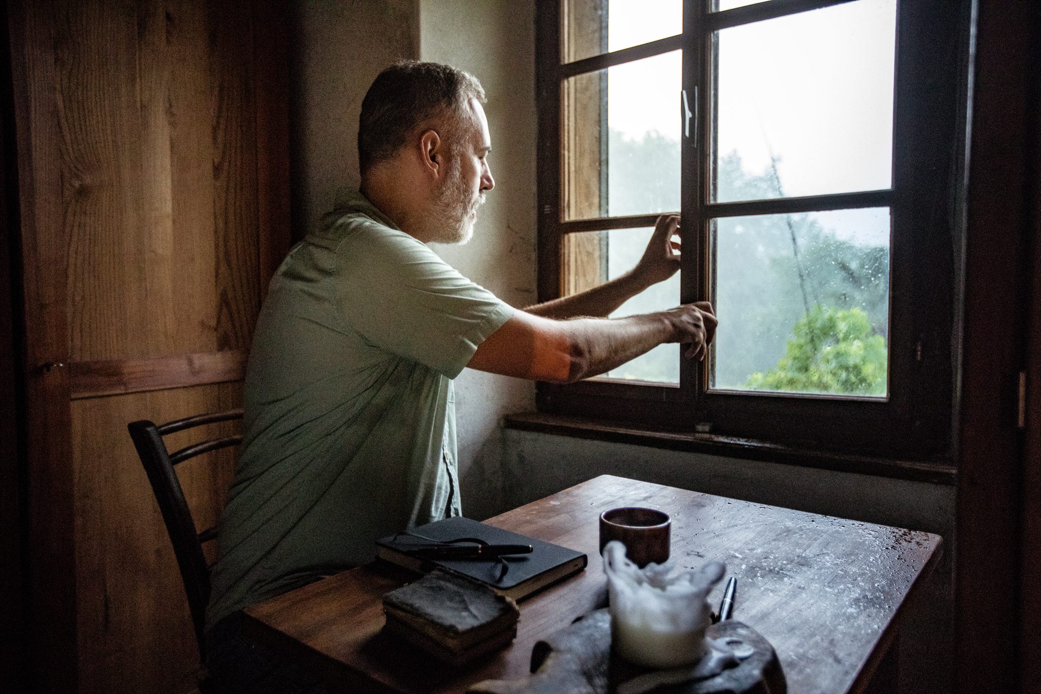 man closing window in home
