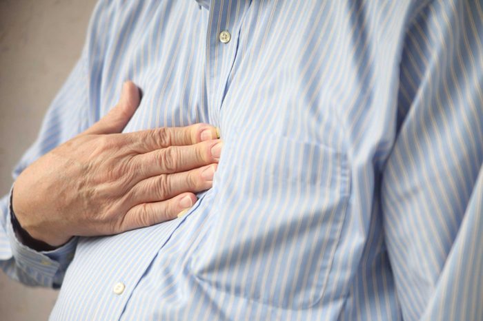 elderly man pressing his hand against his chest