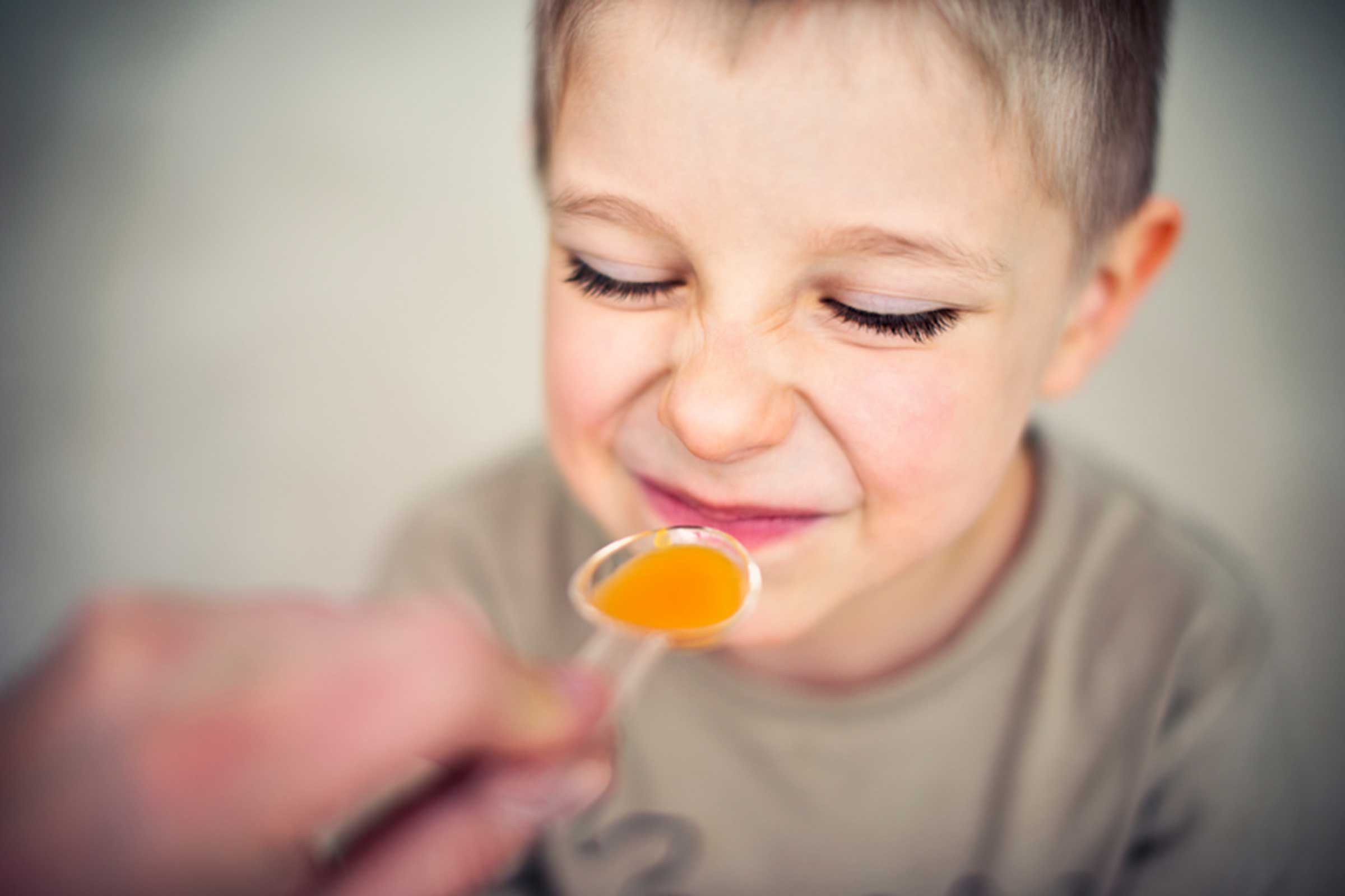 person giving young boy a spoonful of medicine