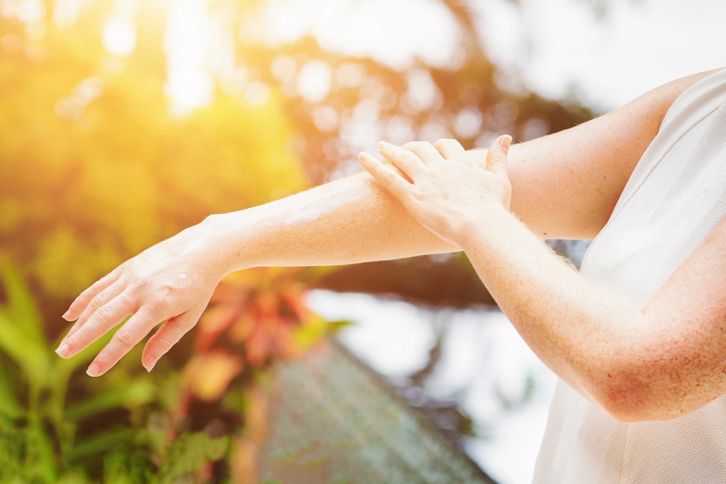 person applying sunscreen to her arm