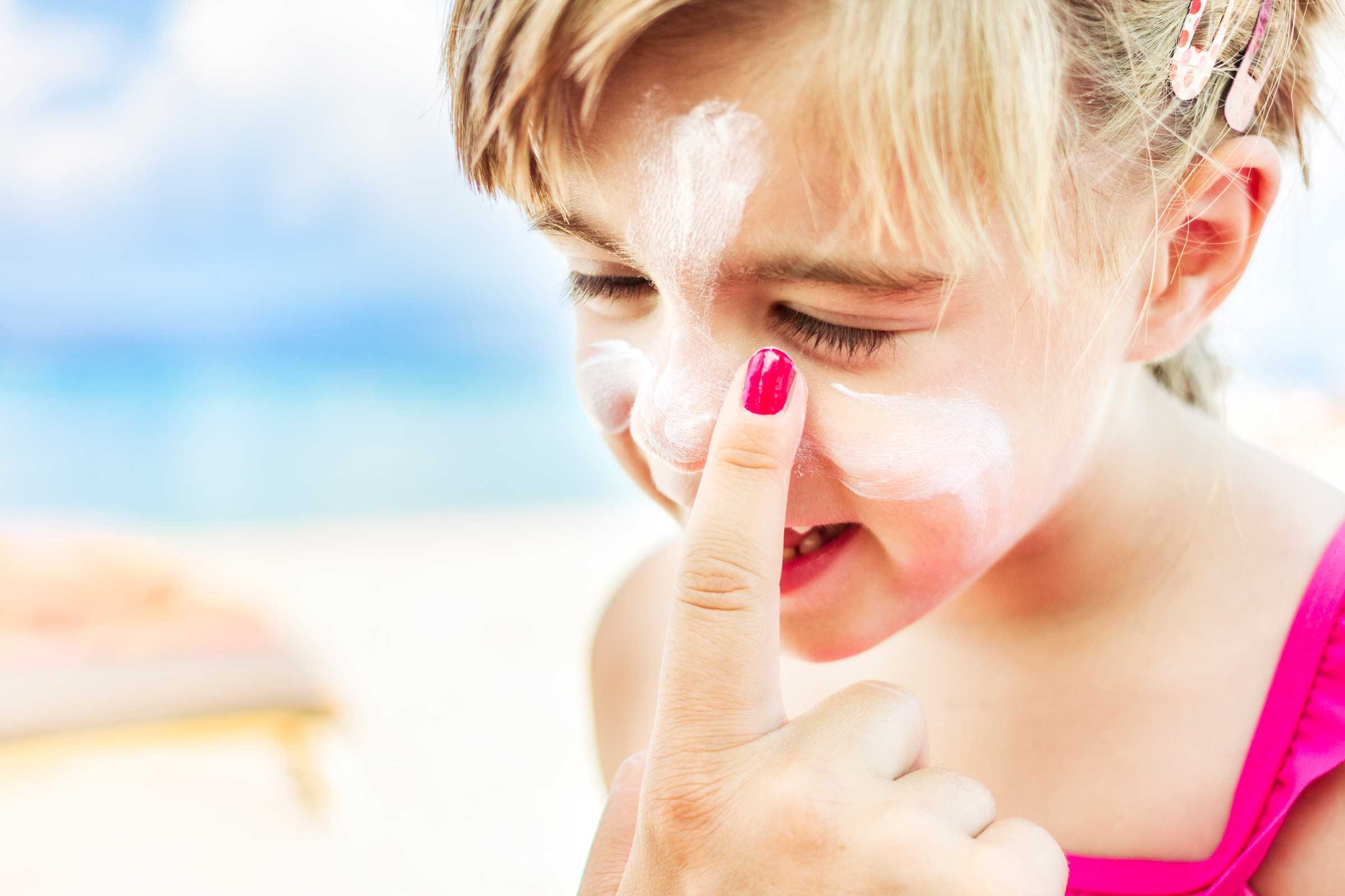 woman applying sunscreen to a child's face