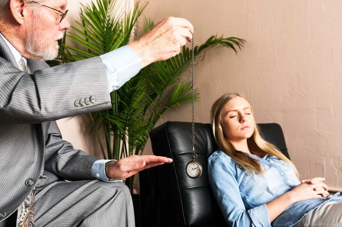 Hypnotist dangling a watch in front of his patient.