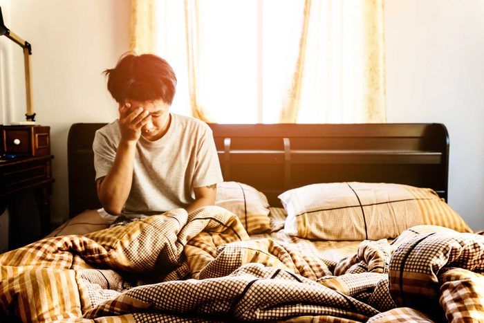 man sitting in bed, head in hand