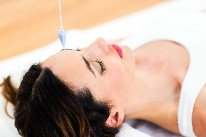 Woman lying on a table with a crystal above her.