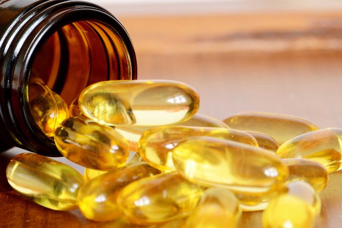 yellow translucent capsules spilling out of a bottle