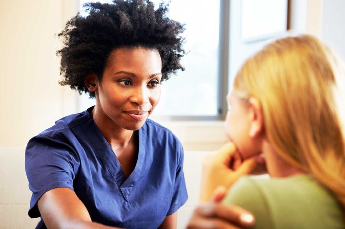 Nurse putting a reassuring hand on another woman's shoulder.