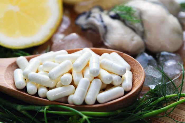 wooden spoon with pills surrounded by lemon and oysters