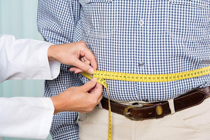 Woman measuring man's waist with measuring tape