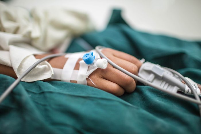 Person's hand hooked up to an IV drip in the hospital.