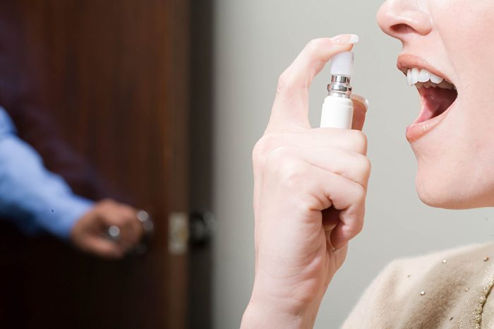 Woman spraying breathe freshener in mouth