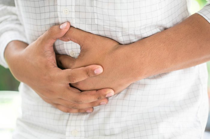man clenching his stomach in discomfort