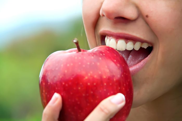a woman taking a bit out of an apple