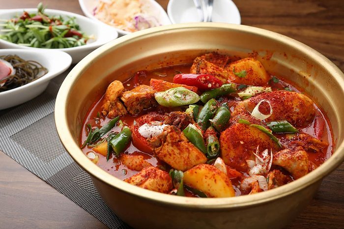 Spicy food with green onions in a bowl on a table.