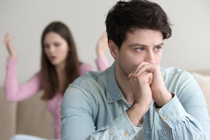 sad man with angry woman in background