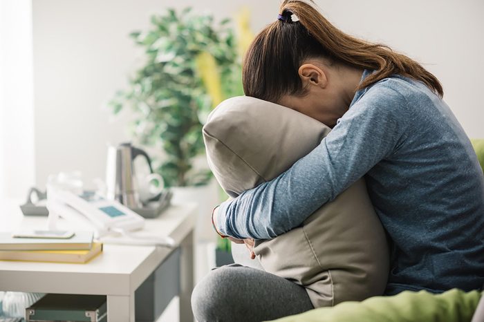 sad woman with face buried in pillow