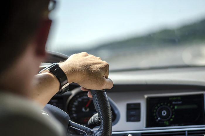 person driving with hand on steering wheel