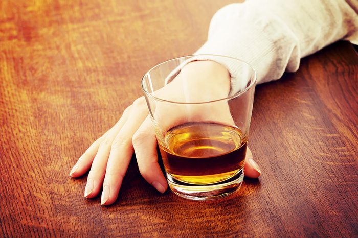 woman's hand holding glass of alcohol