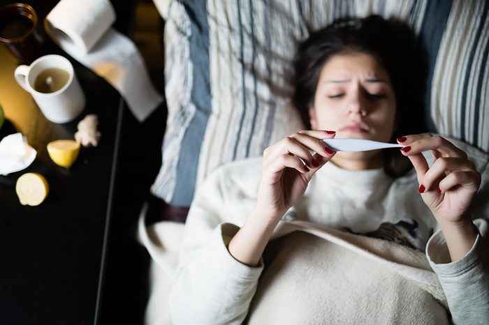 woman checking thermometer in bed
