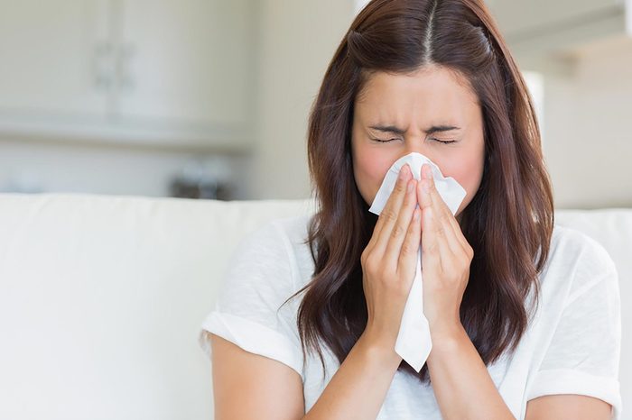 brunette woman sneezing into a tissue
