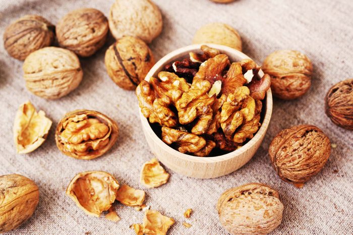 walnuts, some shelled and some unshelled, on a wood surface