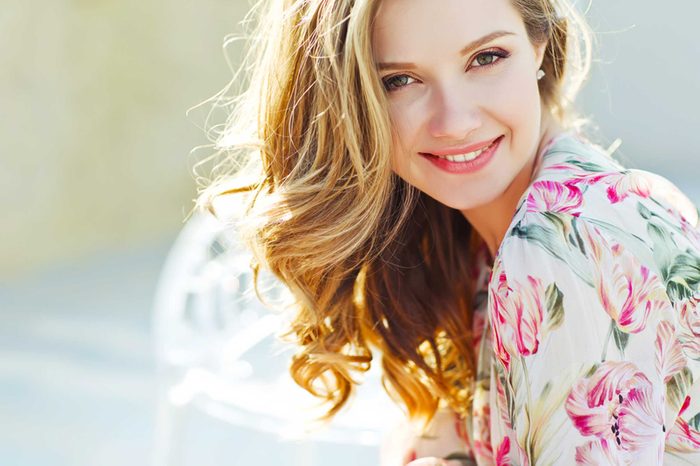 red-haired woman smiling outdoors in the sun