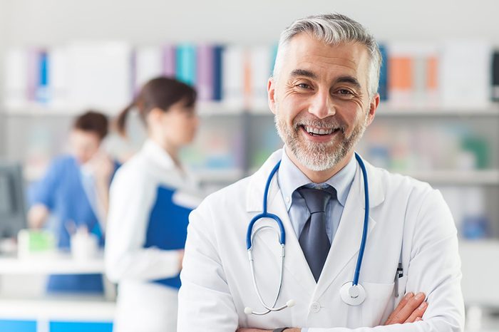 smiling grey-haired doctor in white coat with blue stethoscope