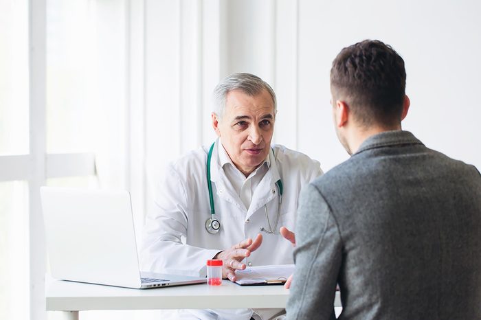 Elderly doctor explaining diagnosis to a young male patient