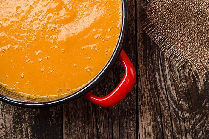 Pot of soup on a wooden table.