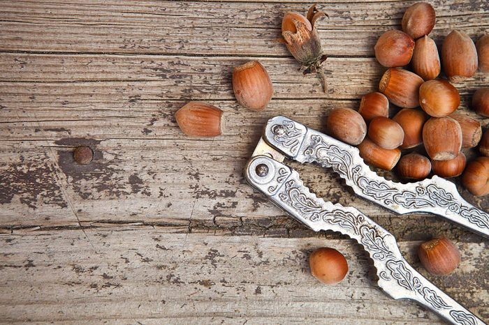 A nutcracker and chestnuts on a wooden table.
