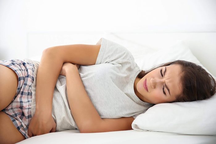 Woman lying down holding her stomach, in pain