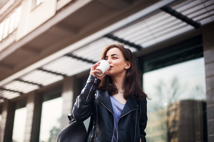 woman walking and drinking coffee