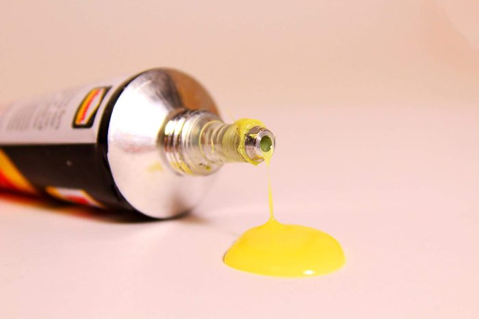 super glue dripping from a tube into a yellow puddle