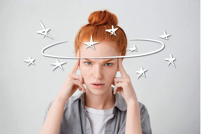red headed woman pressing her fingers against her temples
