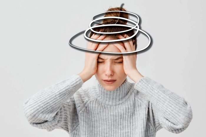 woman holding her head, eyes shut
