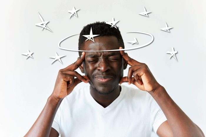 Black man squeezing his eyes shut and holding his temples