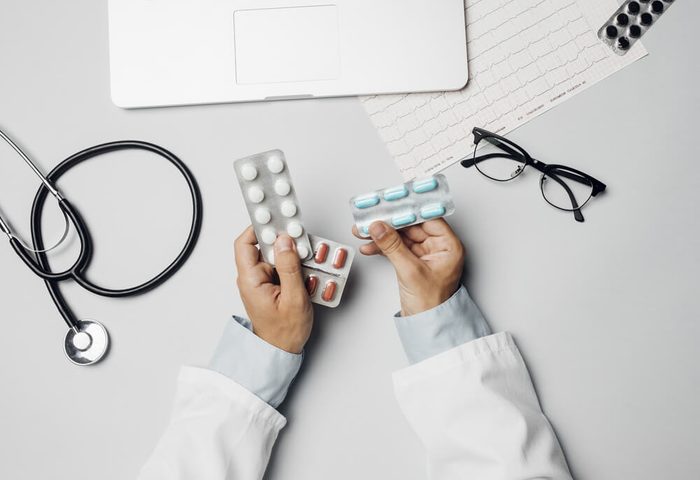 From above photo of hands of cropped men doctor holding pills.