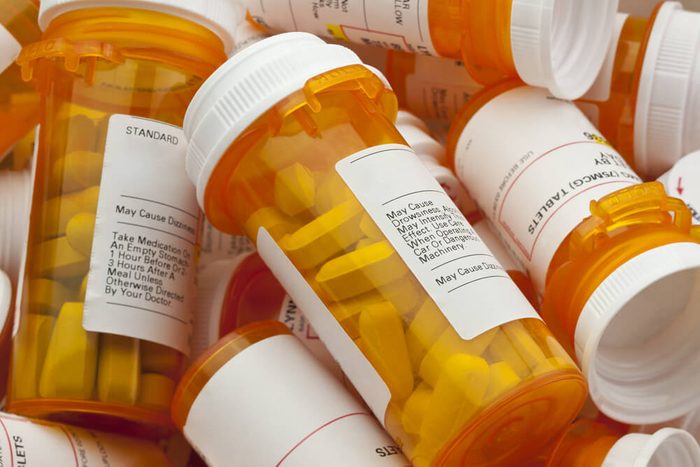 Bottles of prescription medicine in a pile. This collection of pill containers is symbolic of the many medications senior adults and chronically ill people take.