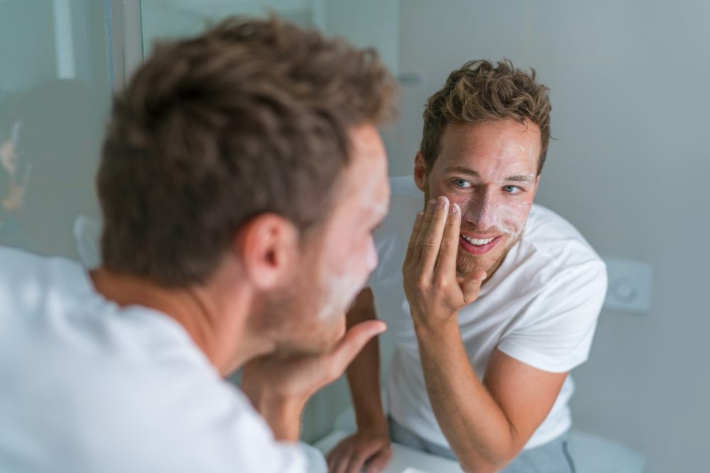 Man washing face with soap scrubbing exfoliation mask
