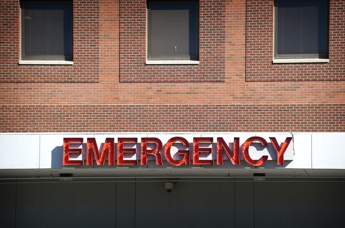 aged and worn vintage photo of neon emergency sign on brick hospital sign