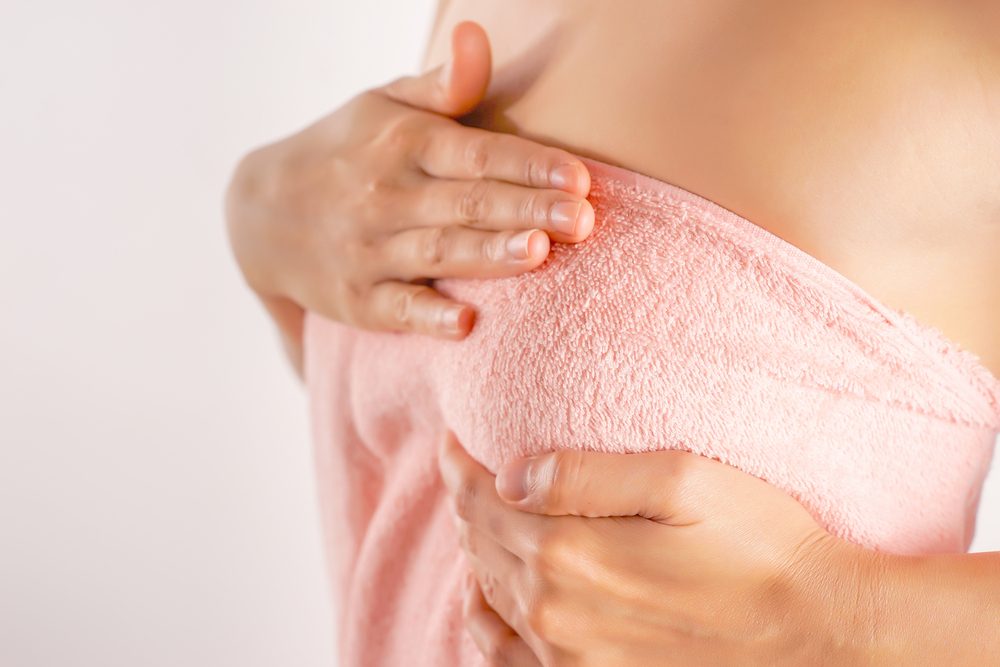 woman wearing towel with hand on her breasts