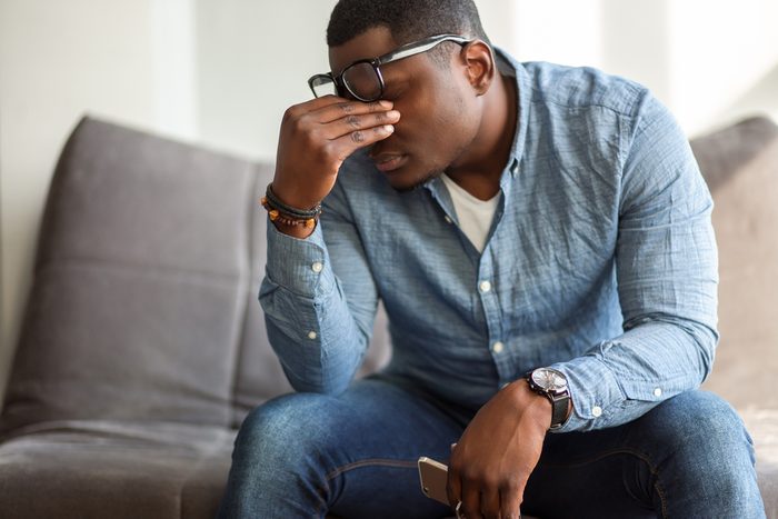 man massaging bridge of his nose with his eyes closed