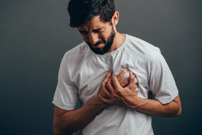 close up of man suffering from heart ache over gray background