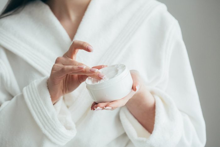 woman's hands holding a jar of beauty cream