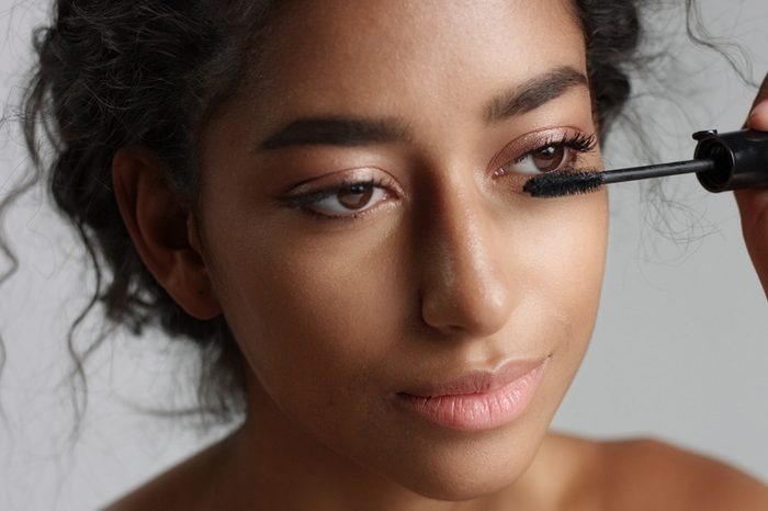 Teenage Middle Eastern girl applying mascara to her lashes