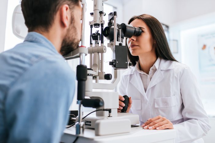 Female ophthalmologist is checking the eye vision of young man in modern clinic. 