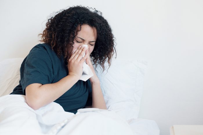 woman in bed, blowing her nose