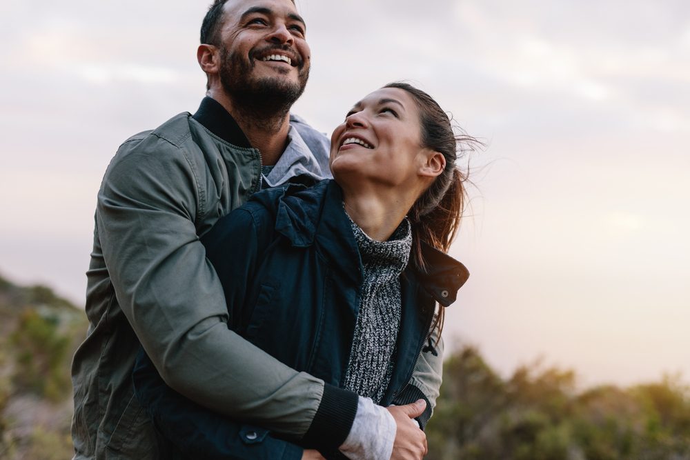 Romantic young couple embracing in nature. Happy young man and woman on vacation in countryside.